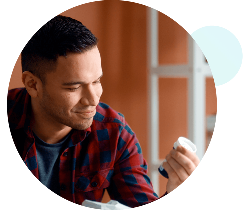 Man holding up a bottle of medication and smiling