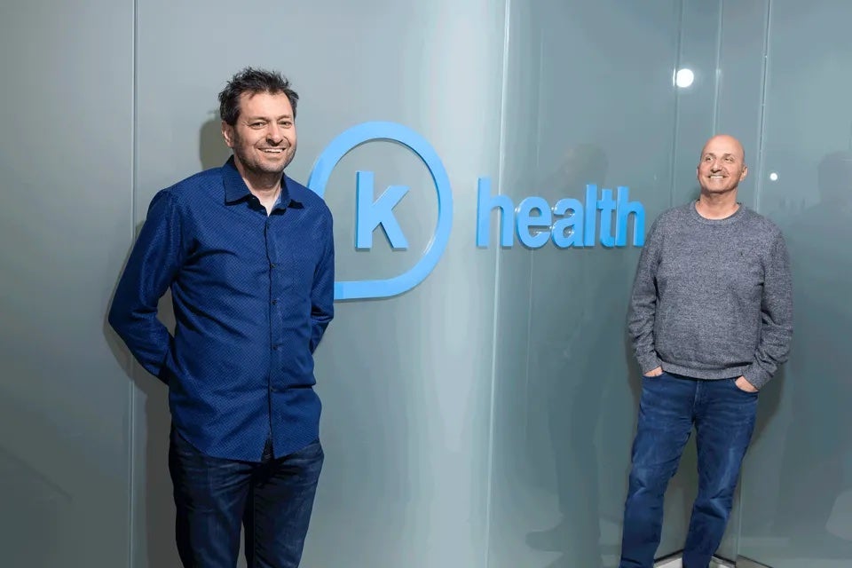 K Health founders Allon Bloch and Ran Shaul stand in front of a K Health sign
